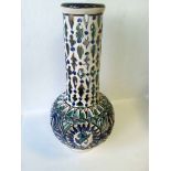 Long neck pierced vase decorated by hand in blues and greens, standing at 26cm tall with printed