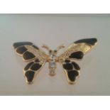 Large brooch in the form of a butterfly. Gold tone with black enamel wings, round cut white stones