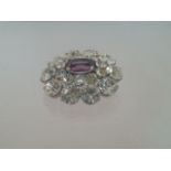 Stunning crystal brooch set with 20 round cut white stones and a central oval cut purple stone.