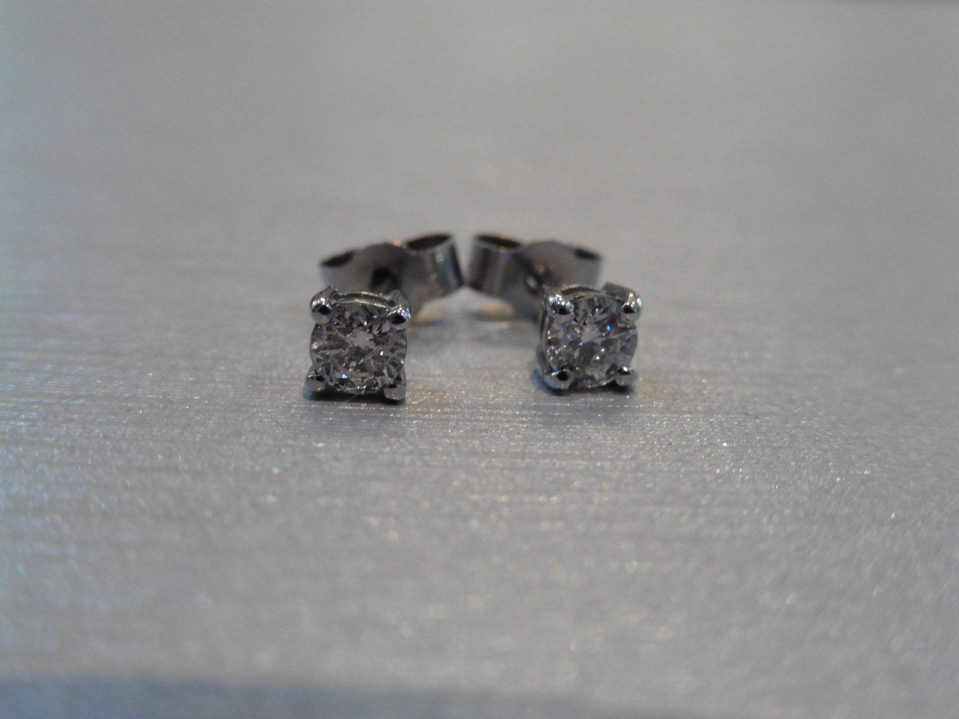 Brand new 18ct white gold solitaire stud earrings each set with a brilliant cut diamond weighing a