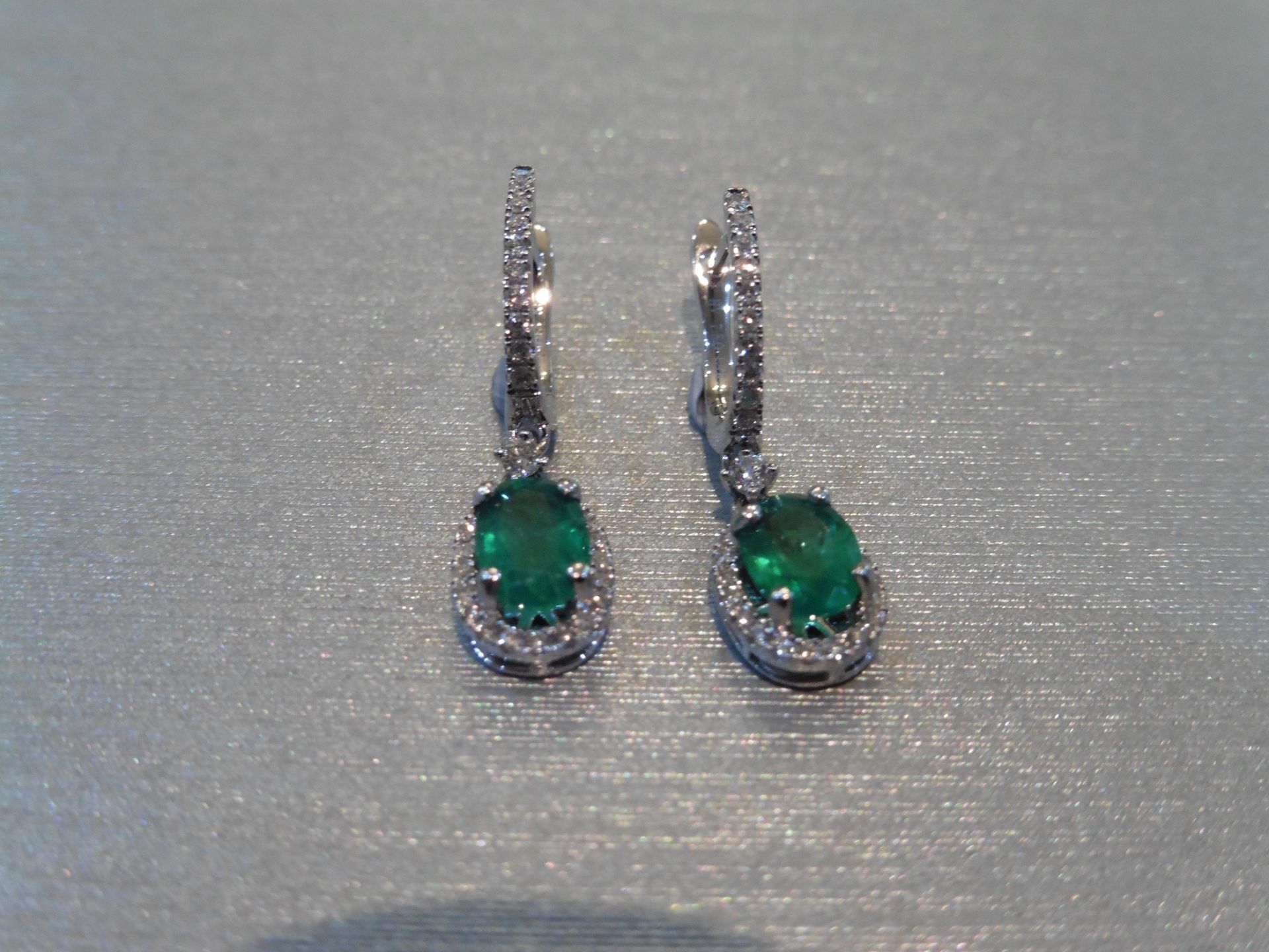 Brand new 18ct white gold emerald and diamond drop style earrings. Each set with an oval cut (