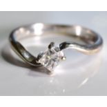 A diamond single-stone crossover ring. The _ square-shape diamond, to the asymmetric shoulders and