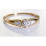 A 9ct gold diamond ring. A single diamond set within an ornate setting with two further diamonds