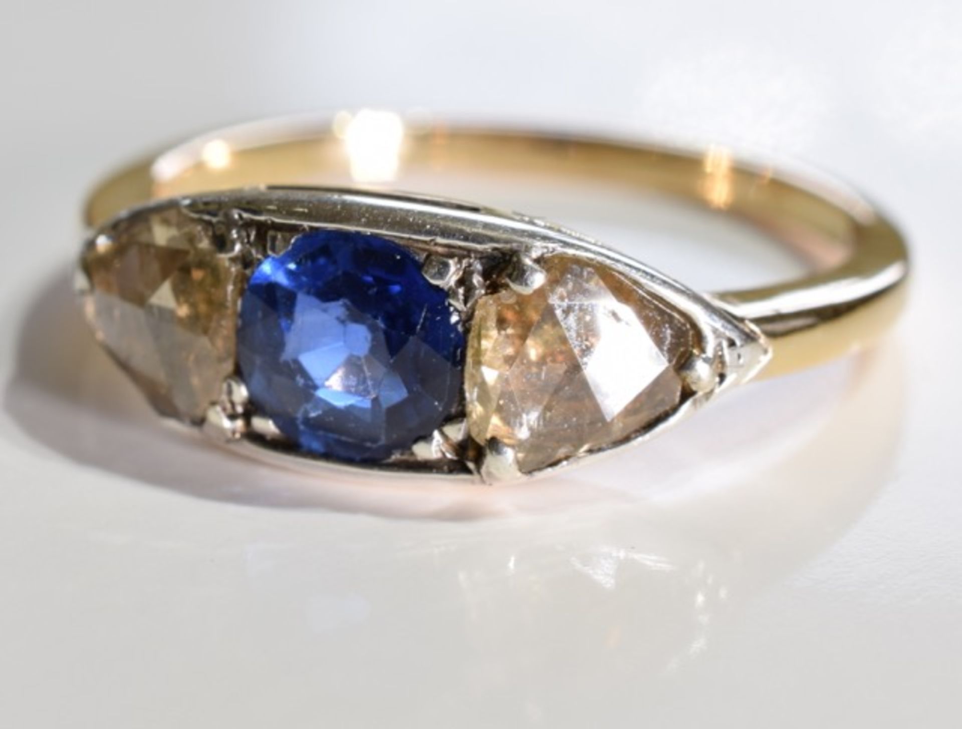 A sapphire and diamond three-stone ring. Size L - The circular-shape sapphire, with triangular-shape