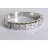 An 18ct white gold diamond ring. A half eternity ring set with brilliant cut diamonds in an 18ct