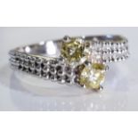 A 18ct white gold crossover ring with two yellow diamonds, well matched. Size M