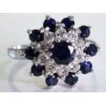An 18ct gold sapphire and diamond cluster ring. The circular-shape sapphire, within a single-cut