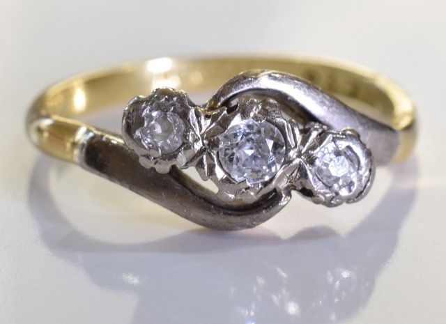 An 18ct Gold and Diamond Crossover ring, Three brilliant cut round graduated diamonds set in a