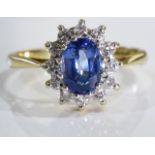 An 18ct gold sapphire and diamond cluster ring. Size L - The oval-shape sapphire, within a