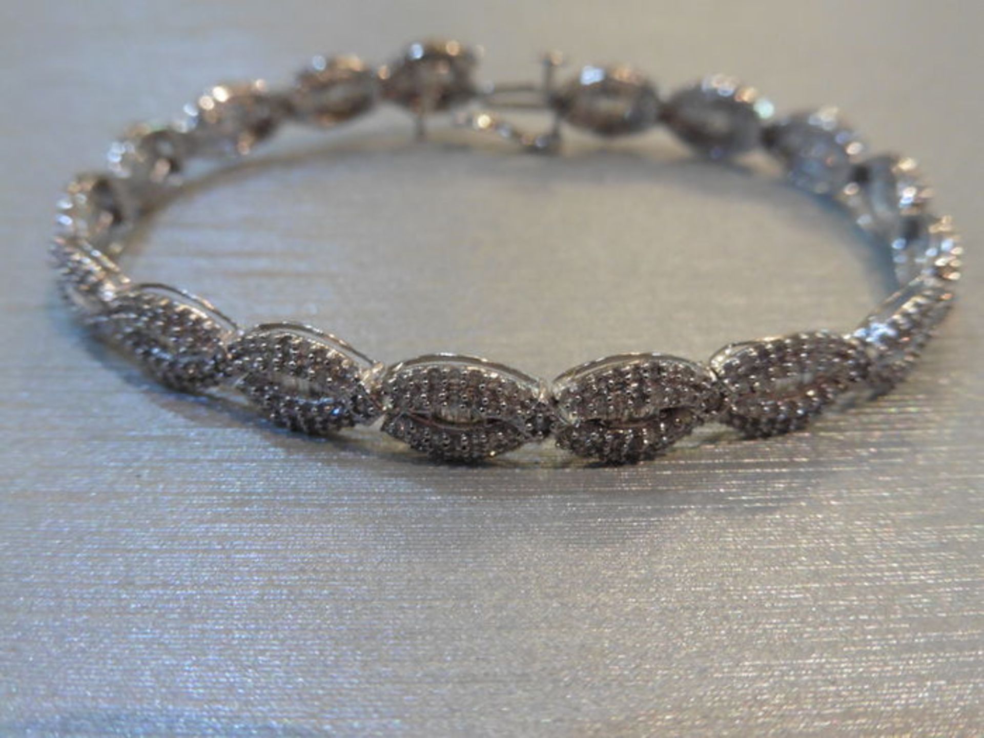 Brand new 10ct white gold fancy diamond bracelet set with oval sections of small baguette cut