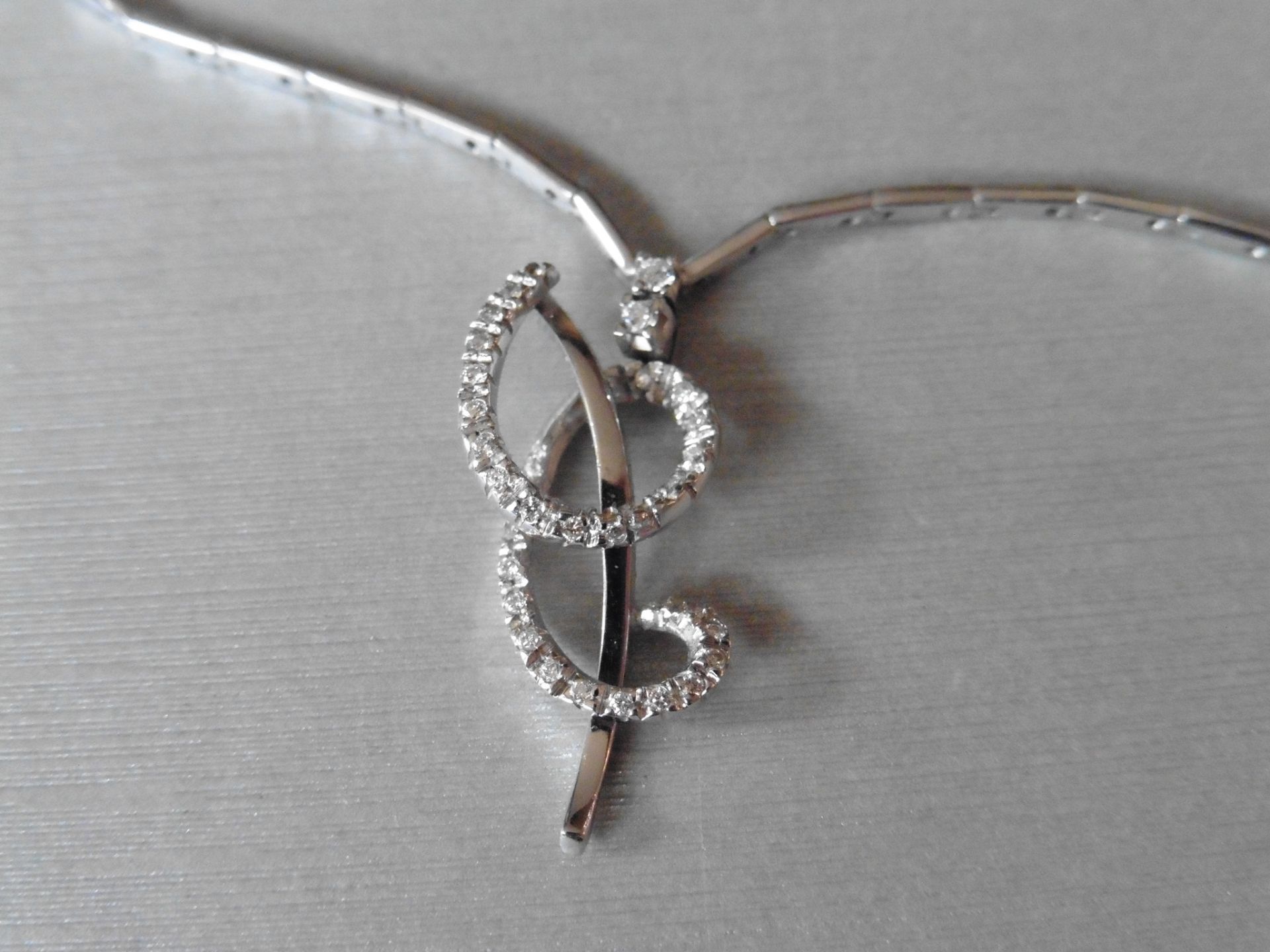 18ct white gold fancy diamond set pendant. Swirl design with small brilliant cut diamonds, H colour,