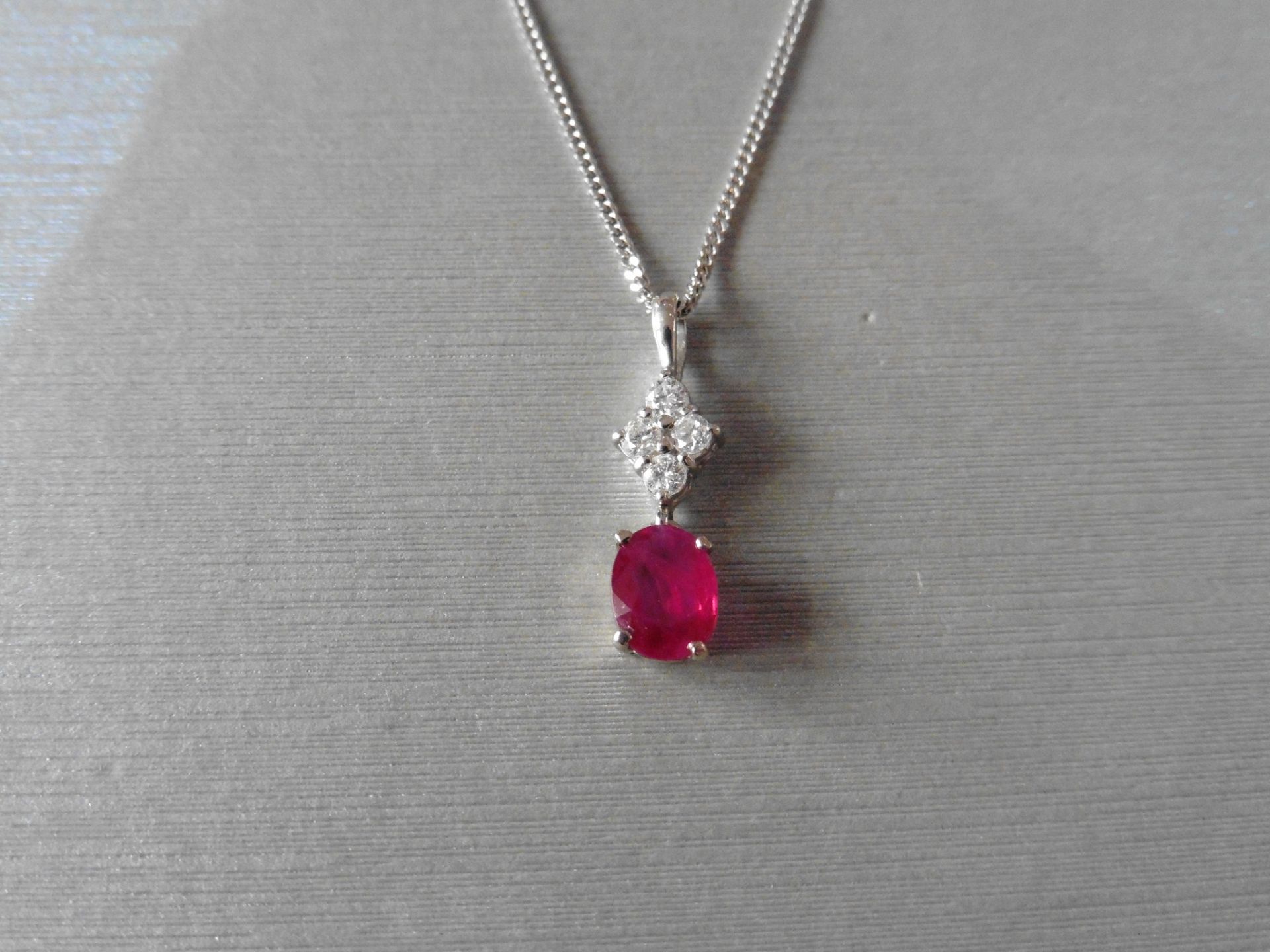 Ruby and diamond pendant set with an oval cut ruby weighing 1.50ct. Set on top are four small