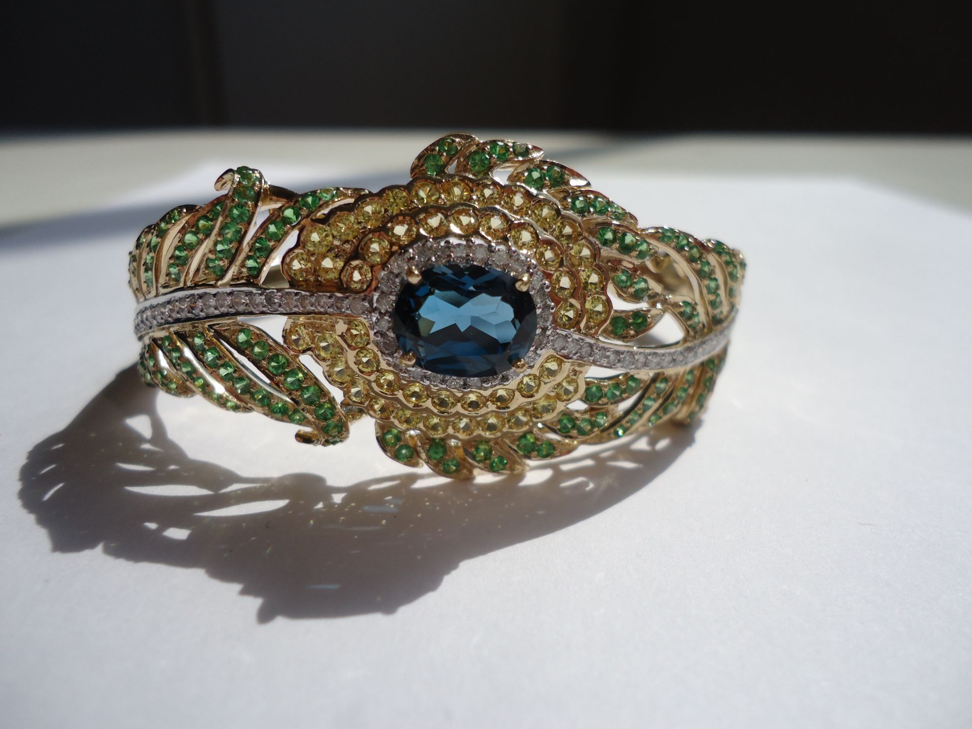 Intricate leaf design bracelet, set on 14k yellow gold with green, yellow and blue precious stoones