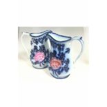 A PAIR OF 19TH CENTURY RELIEF MOULDED FLOW BLUE PITCHERS OR JUGS, HANDPAINTED WITH PINK FLOWER.