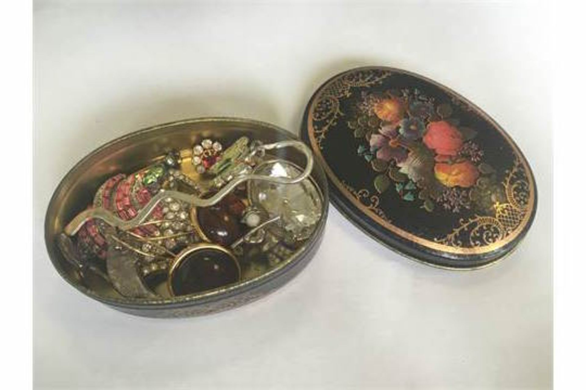 A LACQUERED FLORAL TIN WITH CONTENTS TO INCLUDE VINTAGE EARRINGS, BROOCHES, PENDANTS ETC. FREE UK