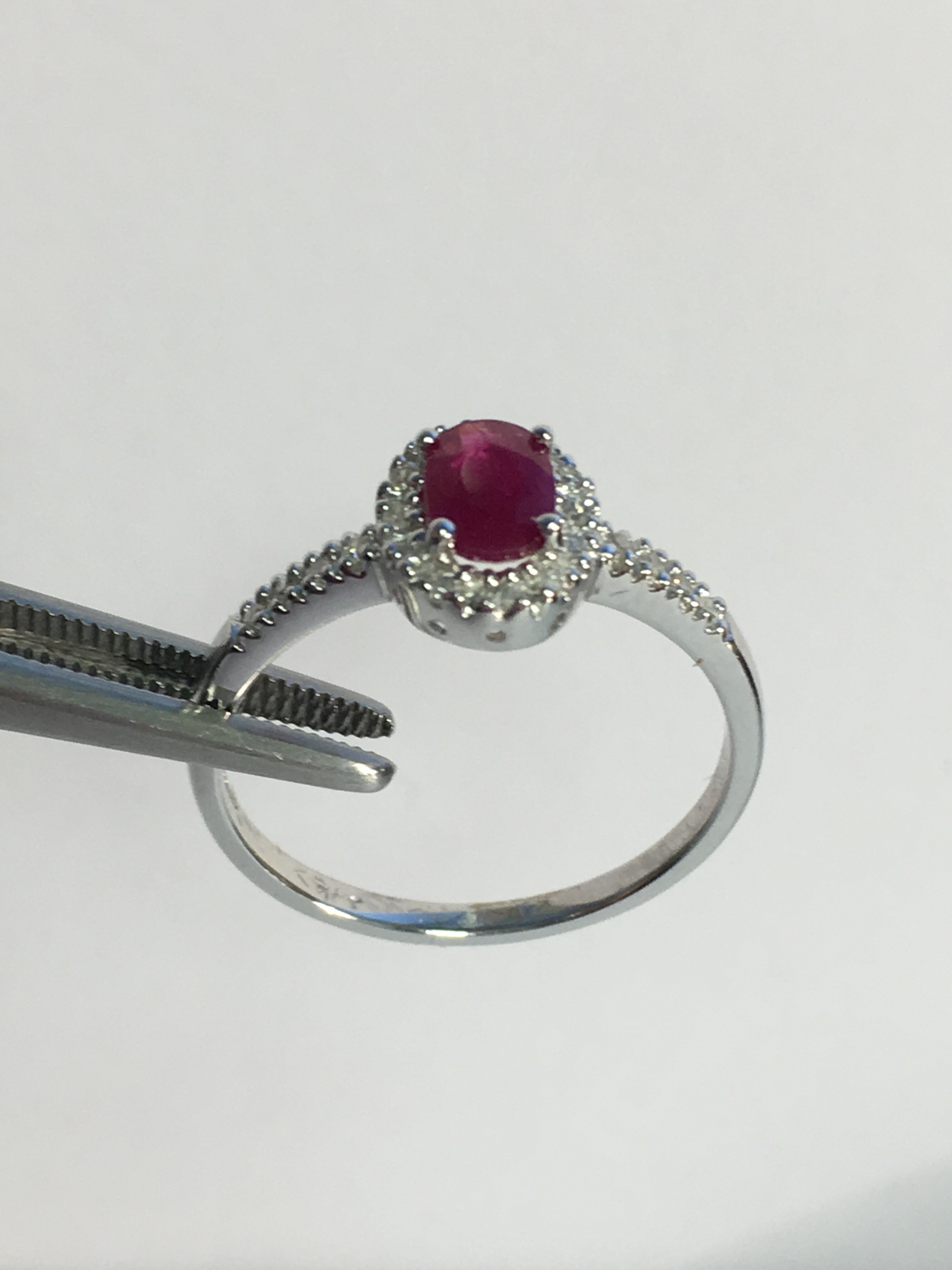 9k White gold ladies ring set with an oval Ruby and diamond surround