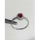 9k White gold ladies ring set with an oval Ruby and diamond surround