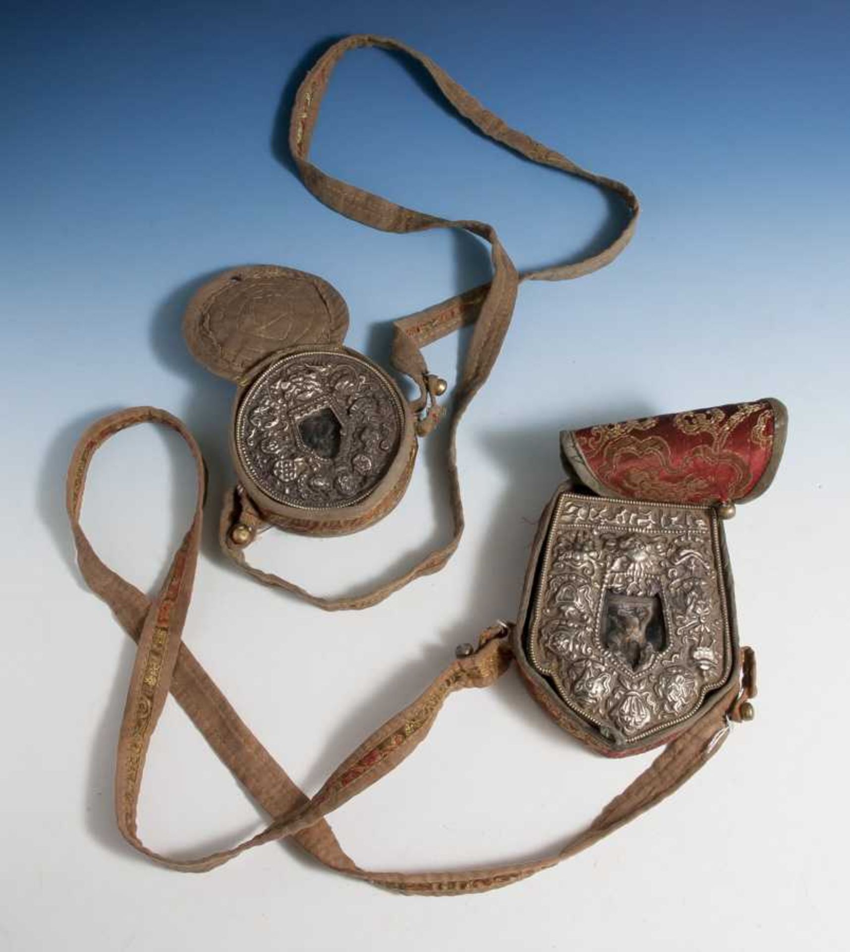 2 Amulettbehälter aus Silber mit Brokat-Etuis, Tibet, 19. Jahrhundert, Altersspuren.