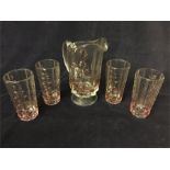 Glass water jug with four matching glasses with raised makers mark.