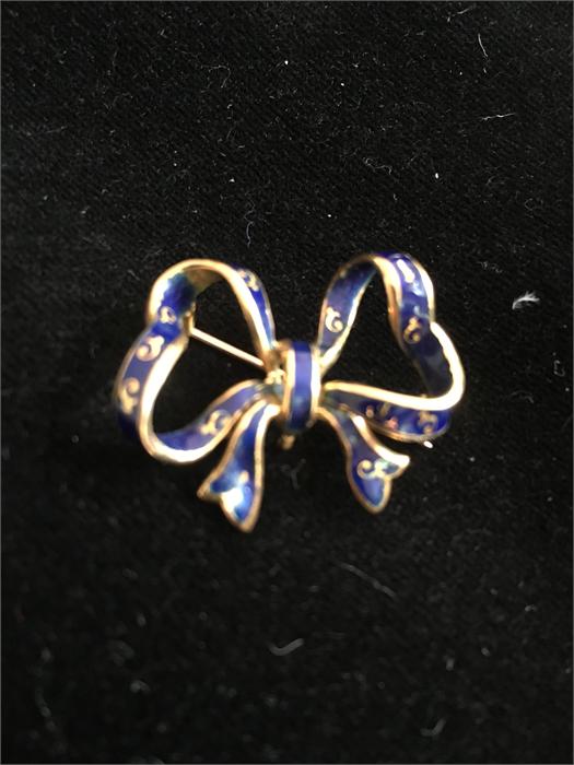 A 18ct gold bow with blue enamel