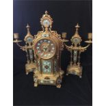 A French gilt brass clock garniture, case marked Brunfaut, with enamelled features.