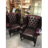 A pair of leather wing back club chairs