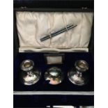A writing set to include a pair of silver candlesticks, silver inkwell, letter opener and calendar