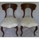A pair of Victorian mahogany dining chairs with shaped top rails, arched supports, fabric