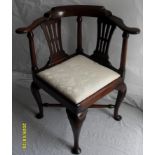 A Georgian mahogany smoker's bow corner chair with carved top rail and arm rests, fabric upholstered