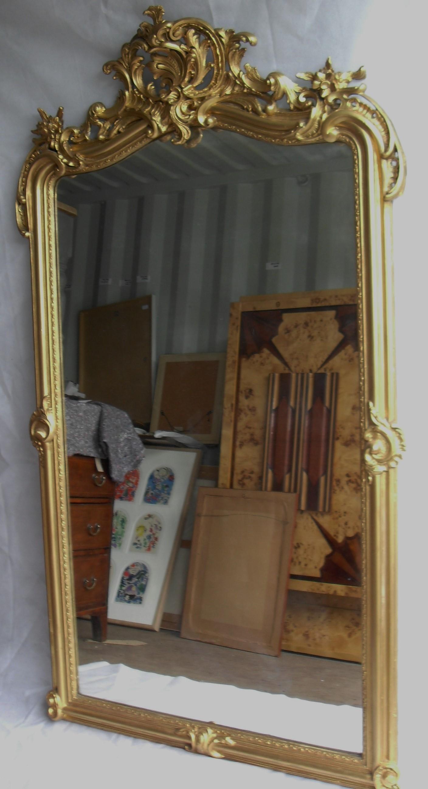 A 19th century gilt-framed console or overmantle mirror with profusely carved cornice depicting '