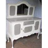 An early 20th century cream-painted sideboard with tray-back domed mirror, central napery drawer and