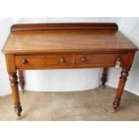 A Victorian mahogany writing or side table with twin frieze drawers on turned legs and castors, in