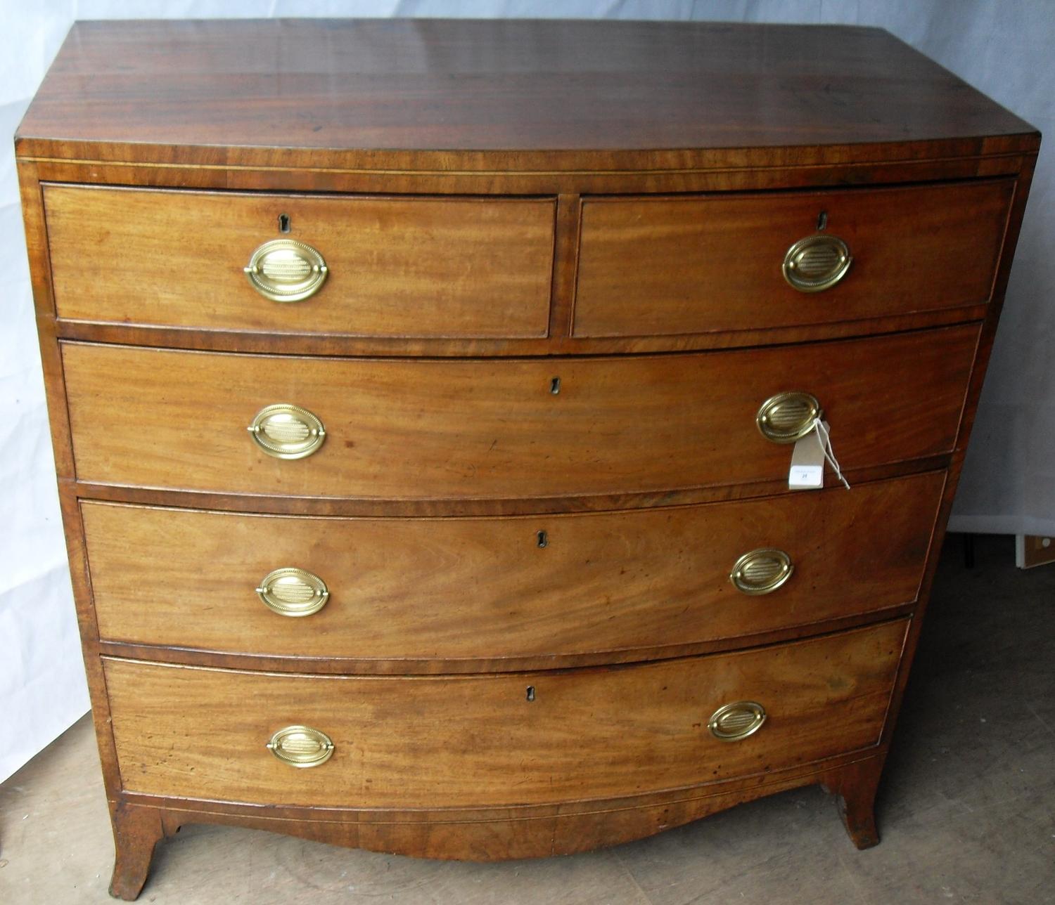 A Georgian mahogany bow-fronted chest of two short and three long graduated drawers with oval