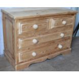 A rustic pine chest of two short and three long drawers with circular handles on a carved plinth, 72