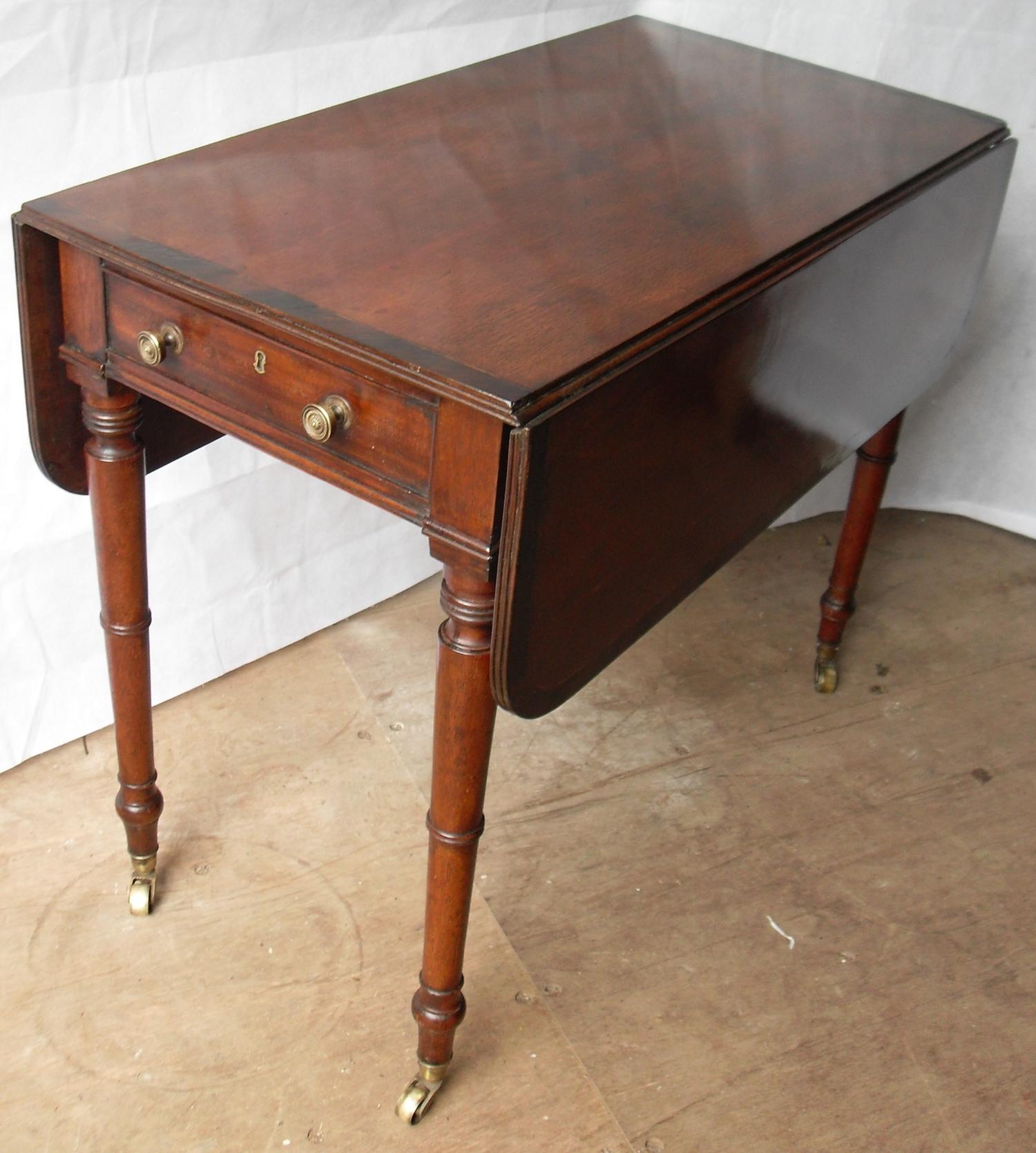 A Regency mahogany Pembroke table with crossbanding to top, twin drop-leaves, frieze drawer with