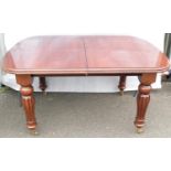 A Victorian-style mahogany pull-out extending dining table with two extra leaves on fluted