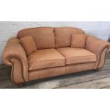 A Thomas Lloyd three-seater leather-upholstered sofa with carved arms on turned legs