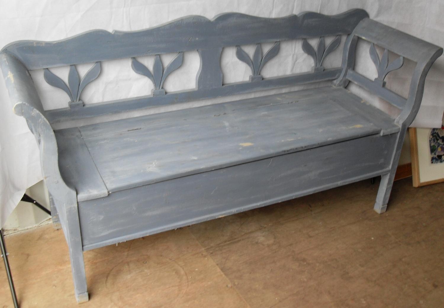 An Eastern European painted bench with floral carved supports and armrests with lift-up seat and