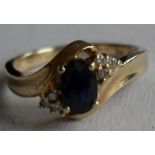 A sapphire and diamond set ring centering on an oval mixed-cut deep blue sapphire measuring 6.02 x