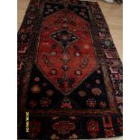 A Persian hand-knotted Hamadan indigo-ground wool rug with contrasting multicoloured isometric