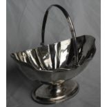 A London silver navette sugar bowl with swing handle and fluted decoration on an oval single foot,