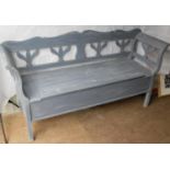 An Eastern European painted bench with floral carved supports and armrests with lift-up seat and