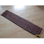 An Uzbek hand-knotted burgundy-ground runner with multicoloured isometric designs, 32 x 147 cm