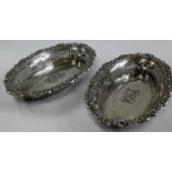 A pair of Edwardian oval silver pierced bread baskets with elaborate 'c' scroll and floral