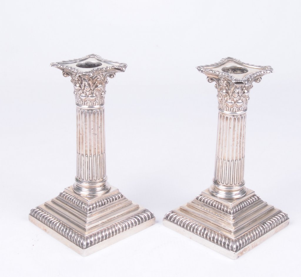 An Edwardian pair of silver Corinthian candlesticks Of typical form,