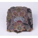 A Victorian embroidered stumpwork and beadwork pin cushion The domed cushion, adorned with amber,