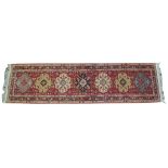 A Turkish style medallion runner of elongated rectangular form, on a predominantly red ground,