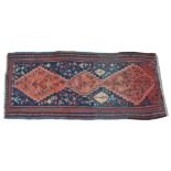 A Kazak style medallion runner Of typical form, with a predominantly navy blue ground,