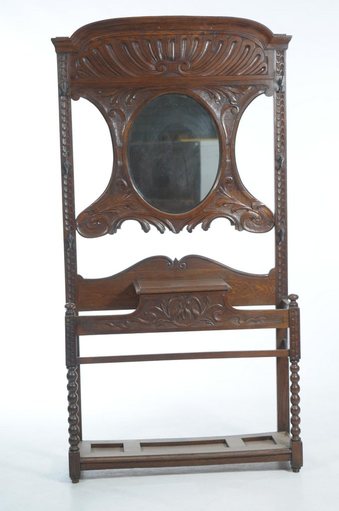 A Late Victorian carved oak hall stand The scrolling leaf carved back centred with an oval mirror