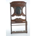 A Late Victorian carved oak hall stand The scrolling leaf carved back centred with an oval mirror